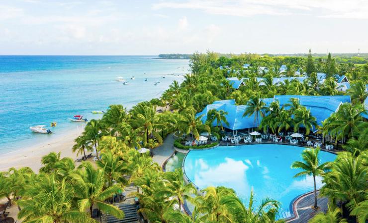 Piesková pláž, more a loďky, kokosové palmy, bazén a reštaurácia hotela Victoria Beachcomber. Maurícius