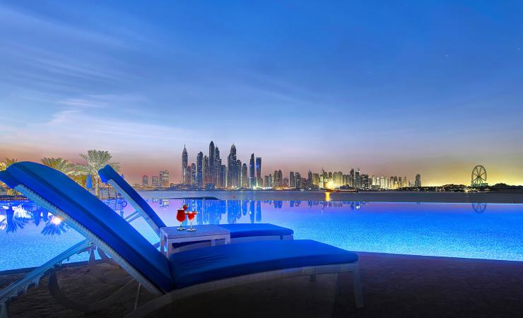 Ležadlá pri bazéne večer v Dukes Dubai, a Royal Hideaway Hotel