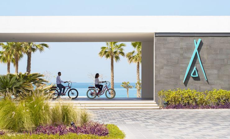 Dvaja ľudia na bicykli pred vstupom do Niki Beach Resort & Spa