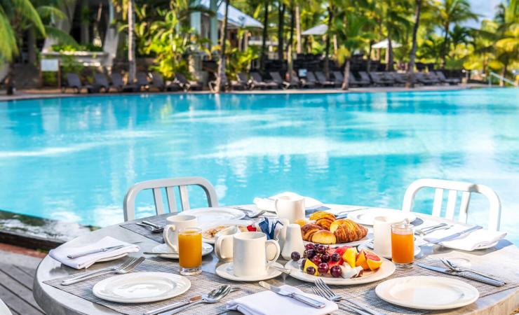 Prestretý stôl na raňajky pri bazéne v hoteli Victoria Beachcomber. Maurícius