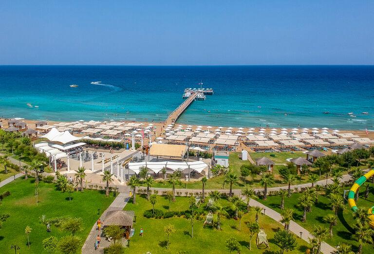 Piesková pláž, slnečníky, reštaurácia a záhrada hotela Limak Cyprus