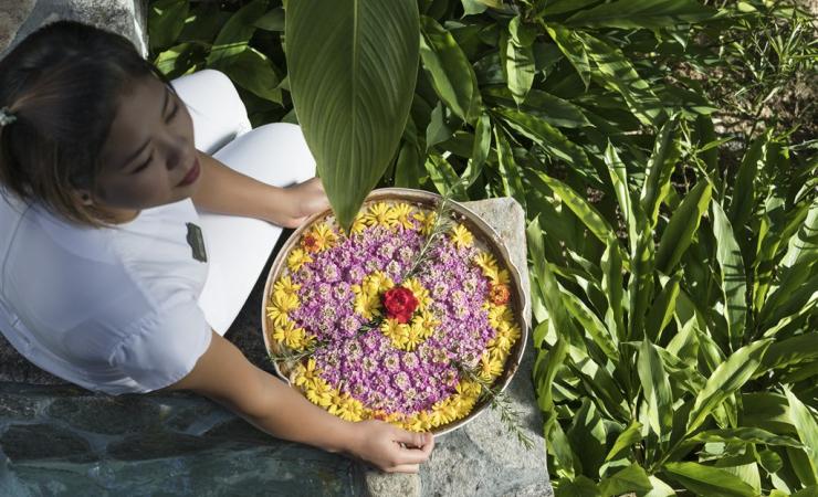 Zamestnankyňa hotela s čerstvými kvetmi na tácke