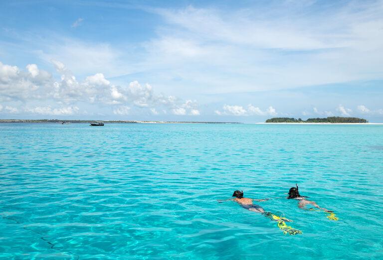 Pláž pred hotelom Emerald Zanzibar Resort and Spa a šnorchlujúca dvojica v mori.