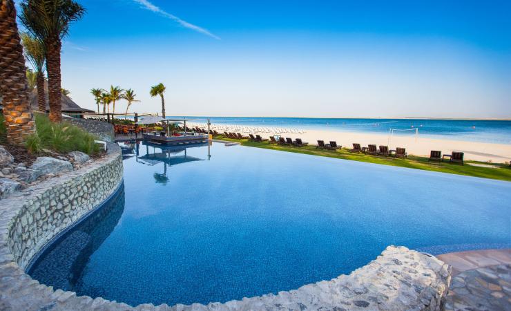 JA Beach hotel s bazénom, pieskovou plážou a tyrkysovým morom.